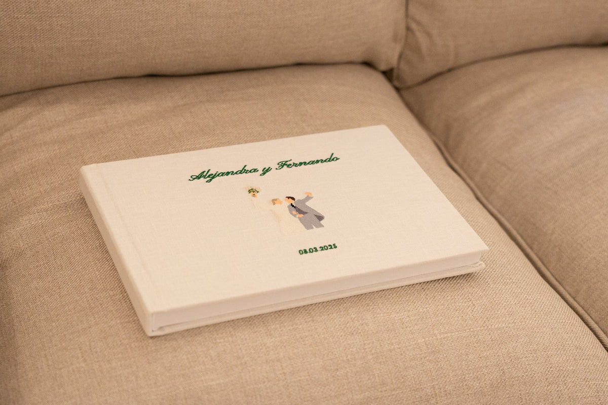 Álbum de boda de lino con los nombres bordados, sobre un sofá