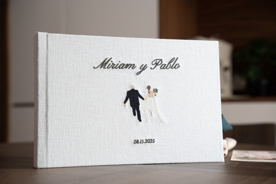 Álbum de boda de lino con los nombres de la pareja y la fecha bordados a mano en la portada
