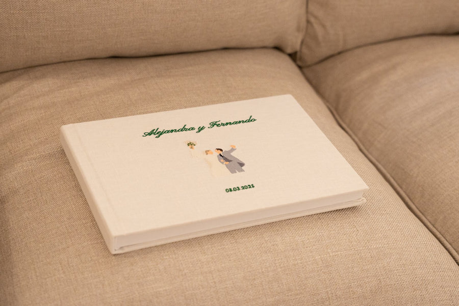 Álbum de boda de lino con los nombres bordados, sobre un sofá